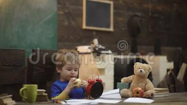 孩子吃多汁的苹果。 金发男孩在上课之间休息。 金发男孩在学校教室里休息吃苹果